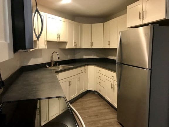 a kitchen with white cabinets and a stainless steel refrigerator at Carisbrooke at Manchester Apartments, Manchester, NH