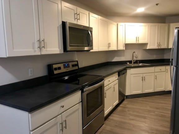 a kitchen with white cabinets and a stainless steel stove and oven and microwave at Carisbrooke at Manchester Apartments, New Hampshire, 03102