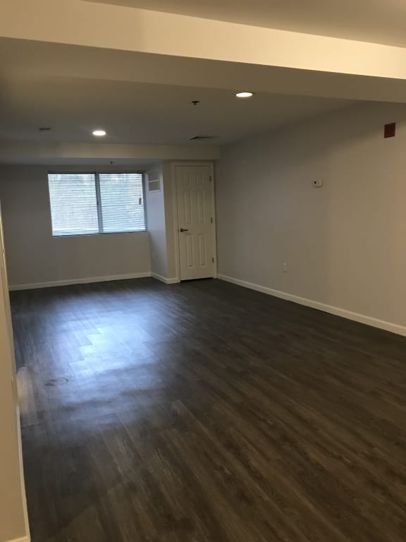 an empty living room with wooden floors and a window at Carisbrooke at Manchester Apartments, Manchester, NH