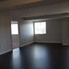 an empty living room with a wood floor and a window at Carisbrooke at Manchester Apartments, Manchester, NH