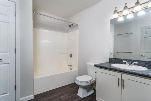 a bathroom with a toilet sink and shower and a mirror at Carisbrooke at Manchester Apartments, Manchester, New Hampshire