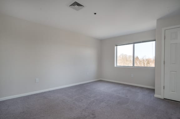 an empty room with a window and a door at Carisbrooke at Manchester Apartments, Manchester, 03102