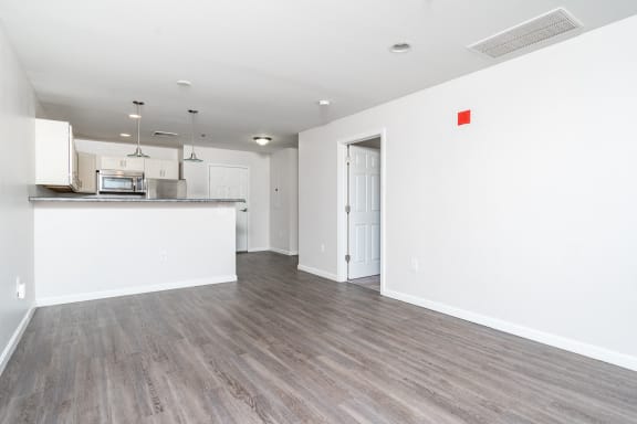 an empty living room and kitchen with white walls and wood flooring at Carisbrooke at Manchester Apartments, Manchester, New Hampshire