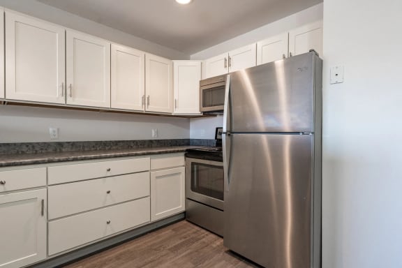 a kitchen with stainless steel appliances and white cabinets at Carisbrooke at Manchester Apartments, Manchester