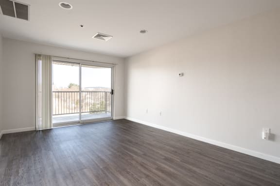 an empty living room with wood floors and a sliding glass door at Carisbrooke at Manchester Apartments, New Hampshire, 03102
