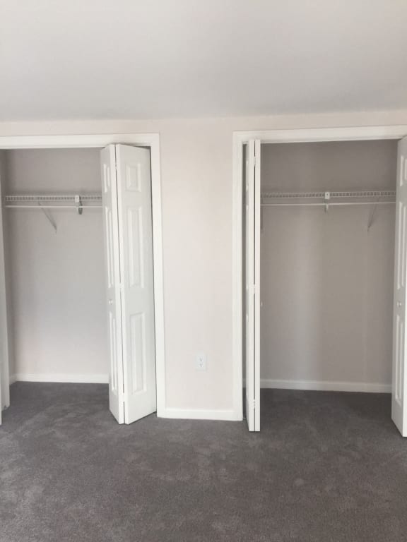 an empty bedroom with two closets and two open doors at Carisbrooke at Manchester Apartments, Manchester, 03102