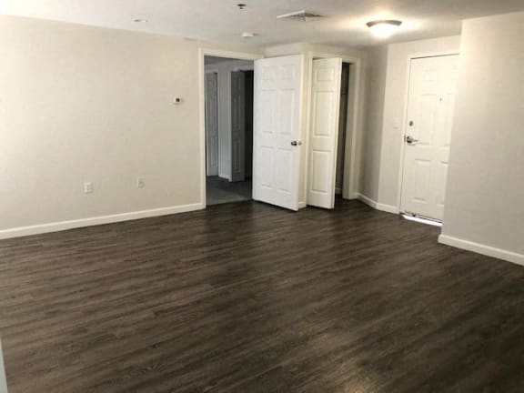 an empty living room with wood floors and white walls at Carisbrooke at Manchester Apartments, Manchester, NH
