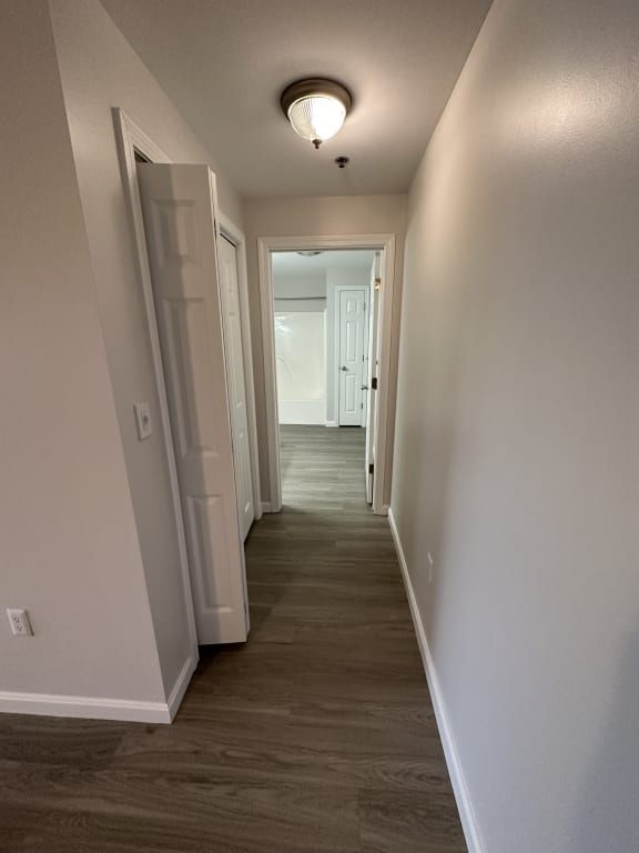 a hallway with wood floors and white walls and a ceiling light at Carisbrooke at Manchester Apartments, Manchester, New Hampshire