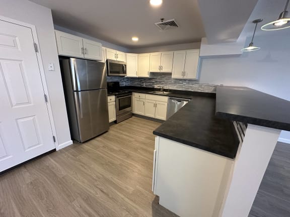 a kitchen with white cabinets and stainless steel appliances at Carisbrooke at Manchester Apartments, Manchester, 03102