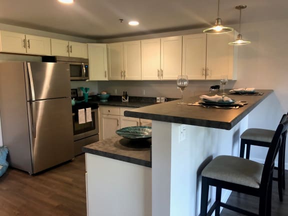 a kitchen with stainless steel appliances and white cabinets at Carisbrooke at Manchester Apartments, Manchester, 03102
