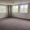 an empty living room with three windows at Carisbrooke at Manchester Apartments, Manchester