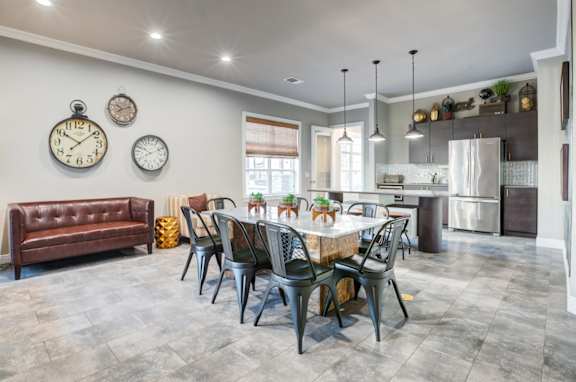 A modern dining room with a brown leather couch, a wooden table, and a kitchen in the background.at Century Ariva, Florida, 33812