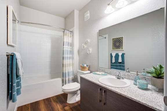 A bathroom with a toilet, sink, and mirror.at Century Ariva, Lakeland, 33812