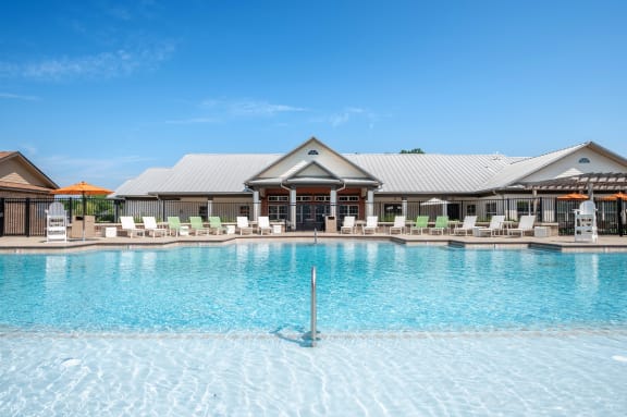 a large pool with lounge chairs and umbrellas in front of a building at Century Belmont Station, Louisville