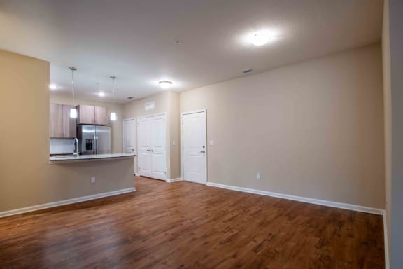 an empty living room and kitchen with wood flooring