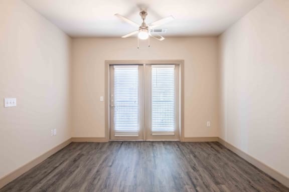 an empty living room with a ceiling fan and window