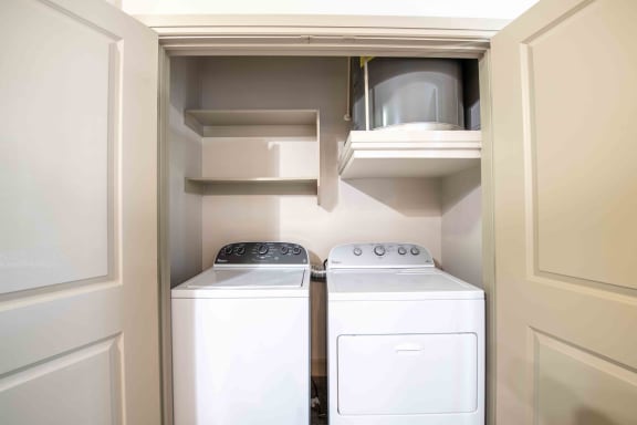 a washer and dryer in a laundry room with white cabinets