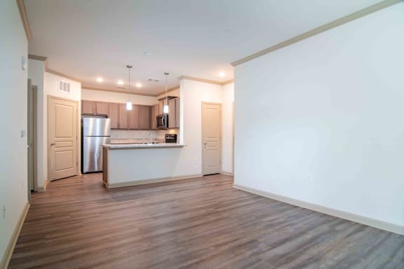an empty living room with a kitchen with a refrigerator and a sink at Century New Holland, Gainesville