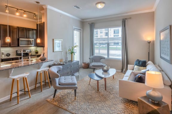 a living room with a kitchen and a couch and chairs