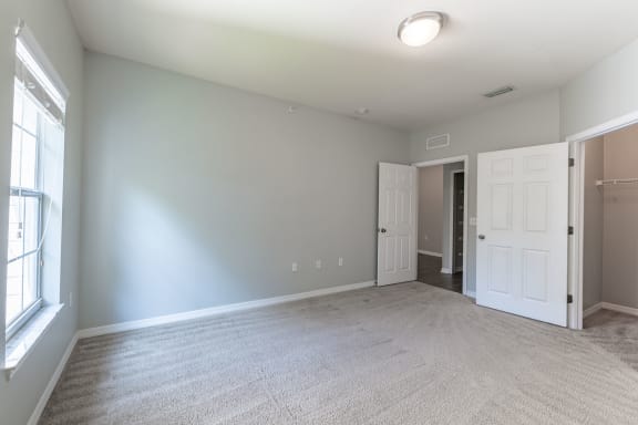 an empty living room with a white carpet and a door to a closet