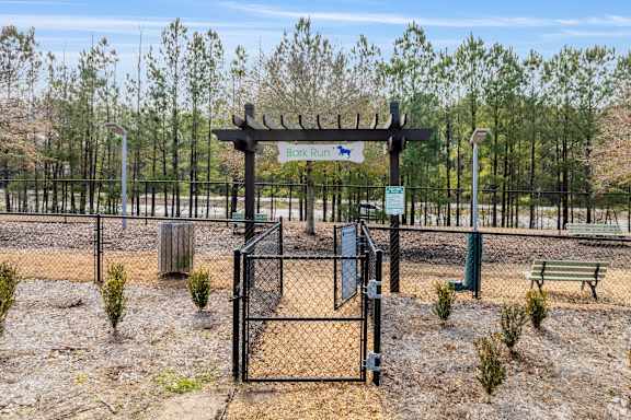 A sign for a dog park is displayed on a fence.