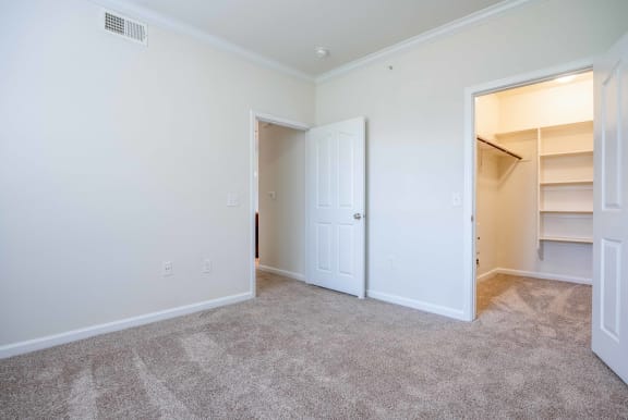 a bedroom with white walls and carpet and a closet