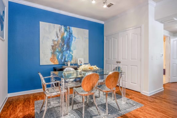 a dining room with a glass table and chairs and a blue wall