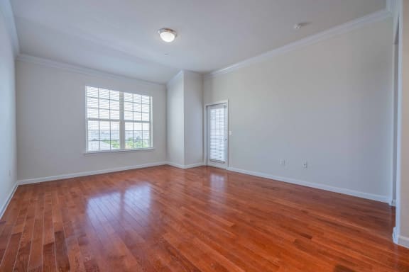 an empty living room with wood floors and a window