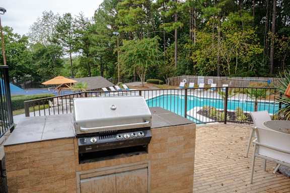 a gas grill on a patio next to a swimming pool at The Carter 4250 Apartments, Georgia 30093