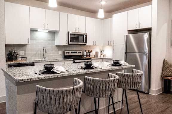 A kitchen with a white counter top and grey chairs.