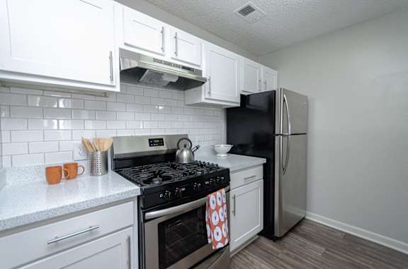 a kitchen with white cabinets and stainless steel appliances and a black refrigerator at The Carter 4250 Apartments, Norcross, GA 30093