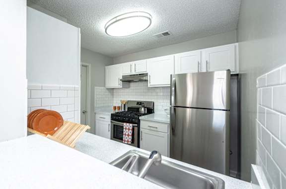 a kitchen with stainless steel appliances and white cabinets at The Carter 4250 Apartments, Norcross, Georgia