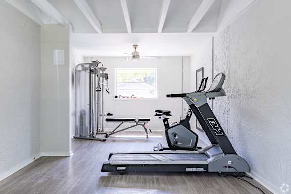 A home gym with a treadmill, exercise bike, and weights.