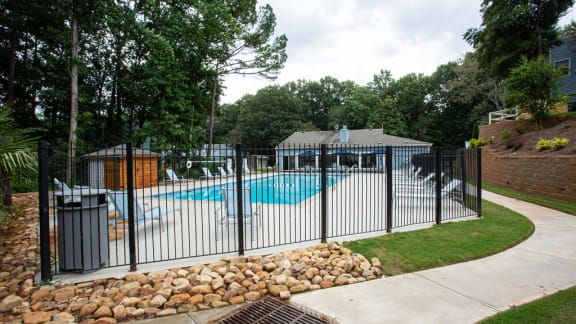 a pool with a black fence and a pool house in the background