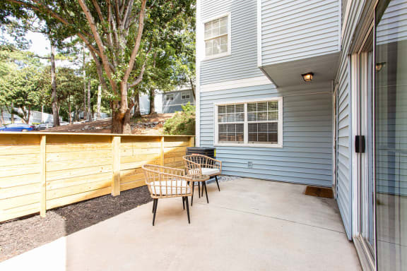 a patio with two chairs and a wood fence at The Cobb Apartments-Townhomes, Georgia