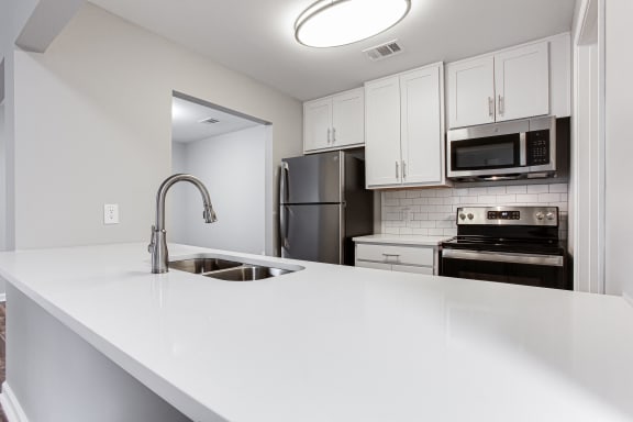 an empty kitchen with white countertops and stainless steel appliances