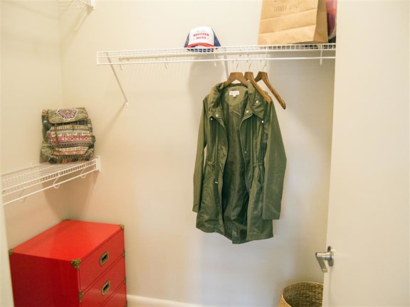 a closet with a red dresser and a green jacket