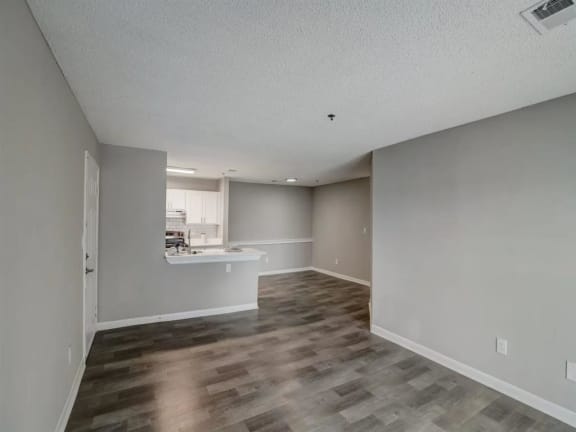 an empty living room and kitchen with a hard wood floor