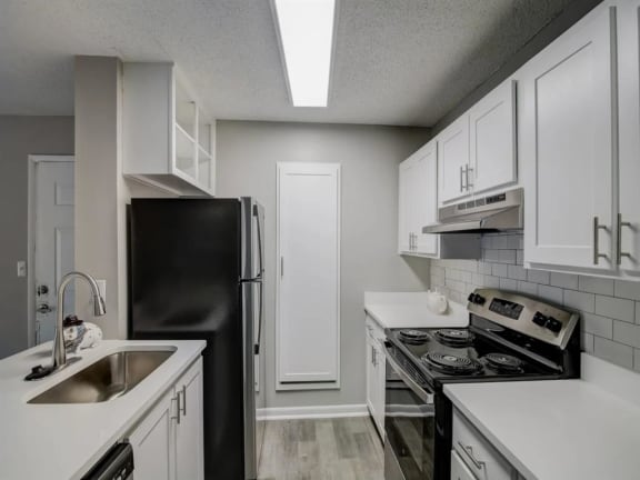 a kitchen with white cabinets and black appliances