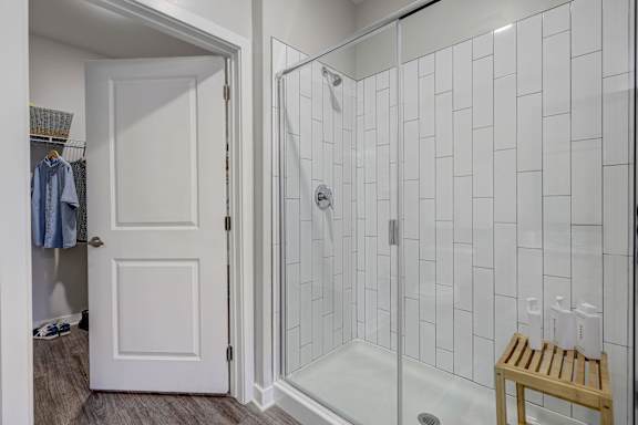 a shower with a glass door in a white tiled bathroom at Century Mundy Mill Apartments, Oakwood 30566