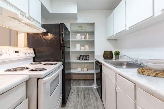A modern kitchen with white appliances and a black refrigerator.