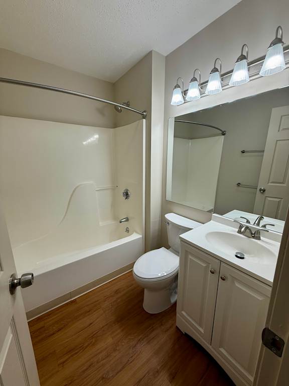 A white toilet sits in a bathroom next to a sink and a bathtub.