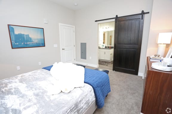 a bedroom with a bed and a sliding door to a bathroom at Century Baxter Avenue, Louisville, KY 40204