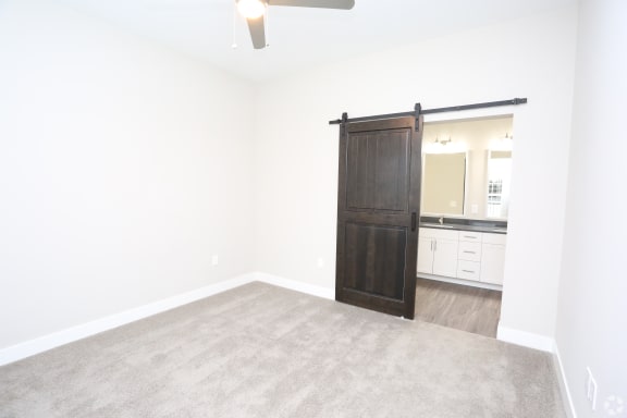 an empty living room with a wooden sliding door to a bathroom at Century Baxter Avenue, Louisville