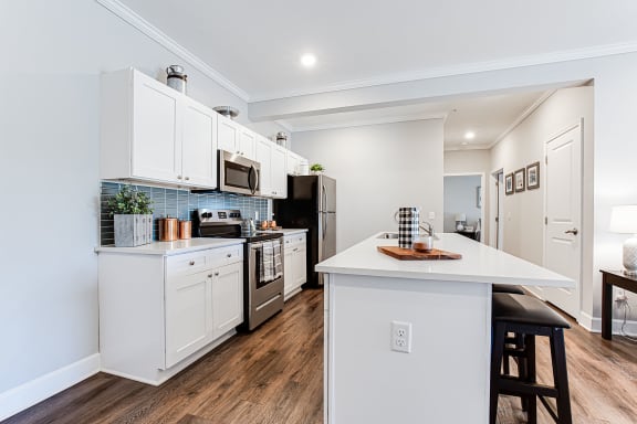 A modern kitchen with white cabinets and a wooden island.