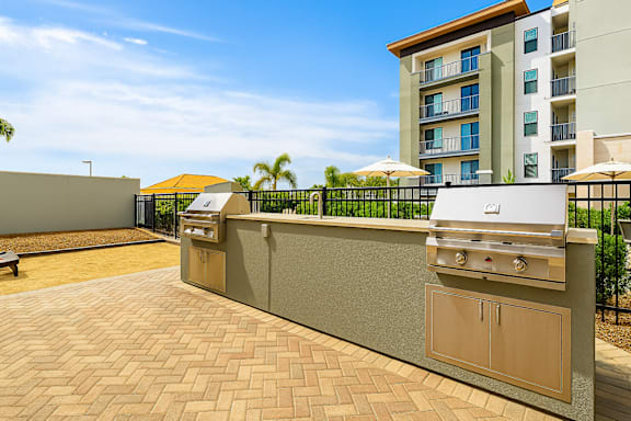 A barbecue grill is on a patio in front of a building.