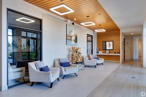 A modern waiting room with grey chairs and a wooden ceiling.