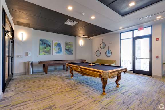 A pool table in a room with a bench and pictures on the wall.