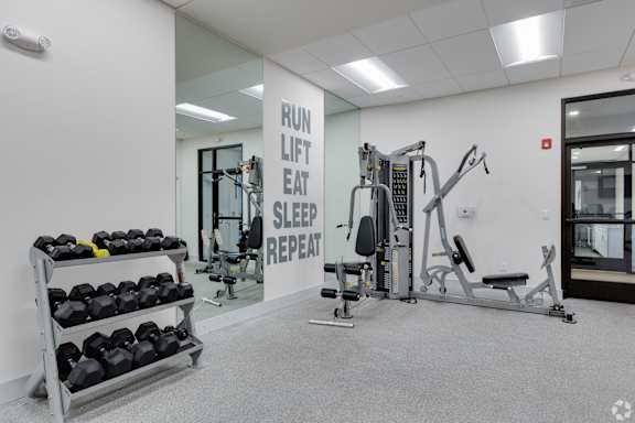 A gym with a sign that says "Run Lift Eat Sleep Repeat".