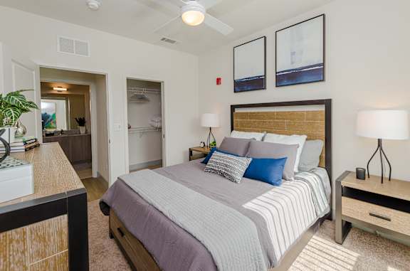 A bedroom with a bed, nightstand, and a plant.